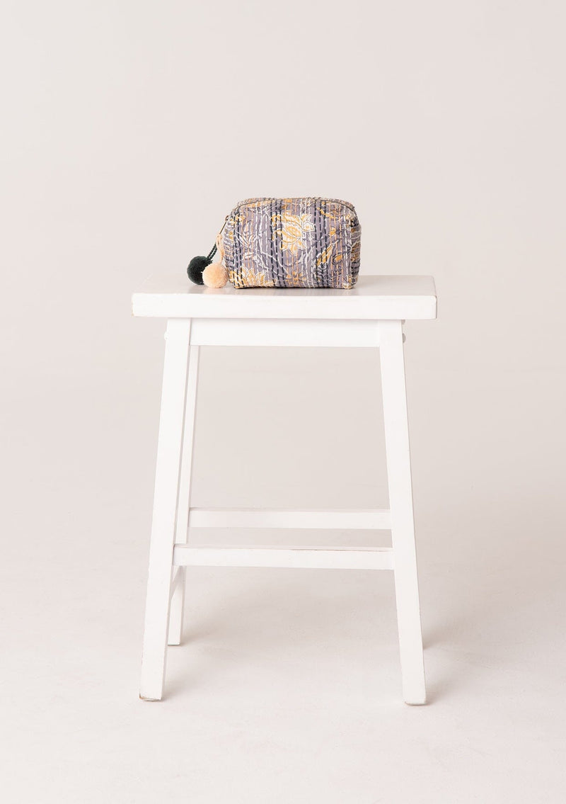[Color: Grey/Yellow] A bohemian small makeup travel bag in a grey and yellow floral print. With a zip closure, stitch details throughout, and a pom accent.