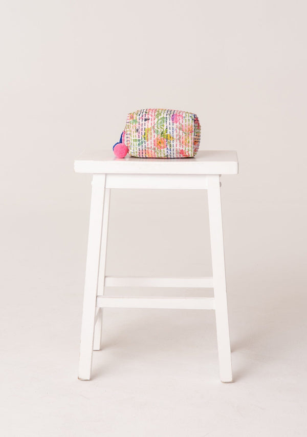 [Color: Off White/Pink] A bohemian small makeup travel bag in a pink and green floral print. With a zip closure, pom accent, and stitch details throughout.