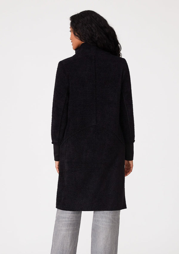 [Color: Black] A back facing image of a brunette model wearing a soft black mid length coat. With long sleeves, a button front, side pockets, and a funnel neckline. 
