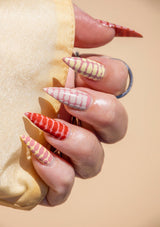 [Color: Petal] Close-up of a hand with long, colorful nails 