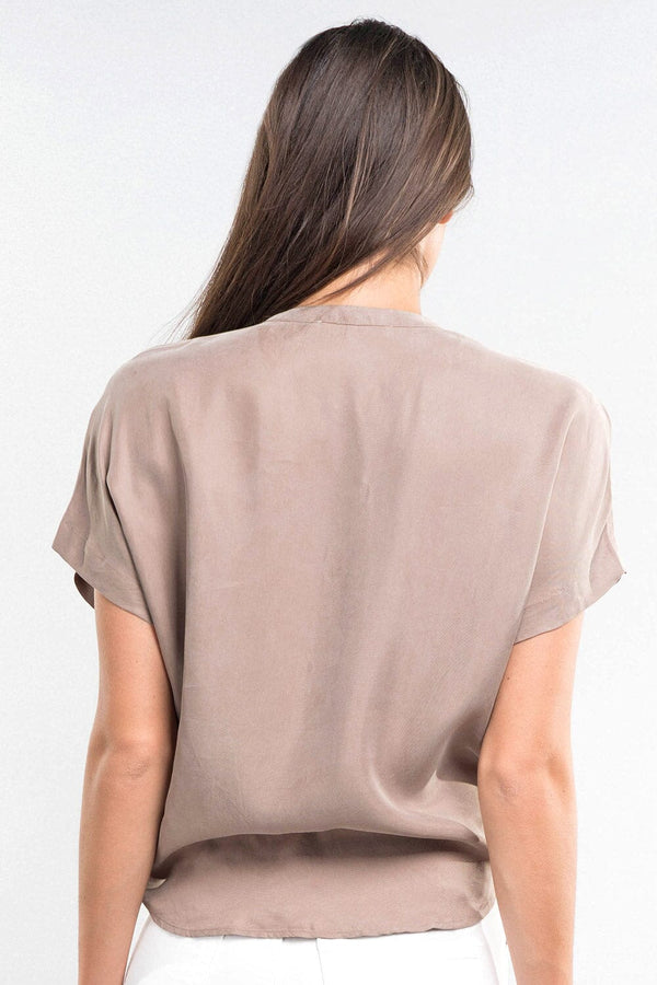 [Color: Mocha] An image of a brunette model wearing a short dolman sleeve top with a button front, single pocket, and tie front detail. 