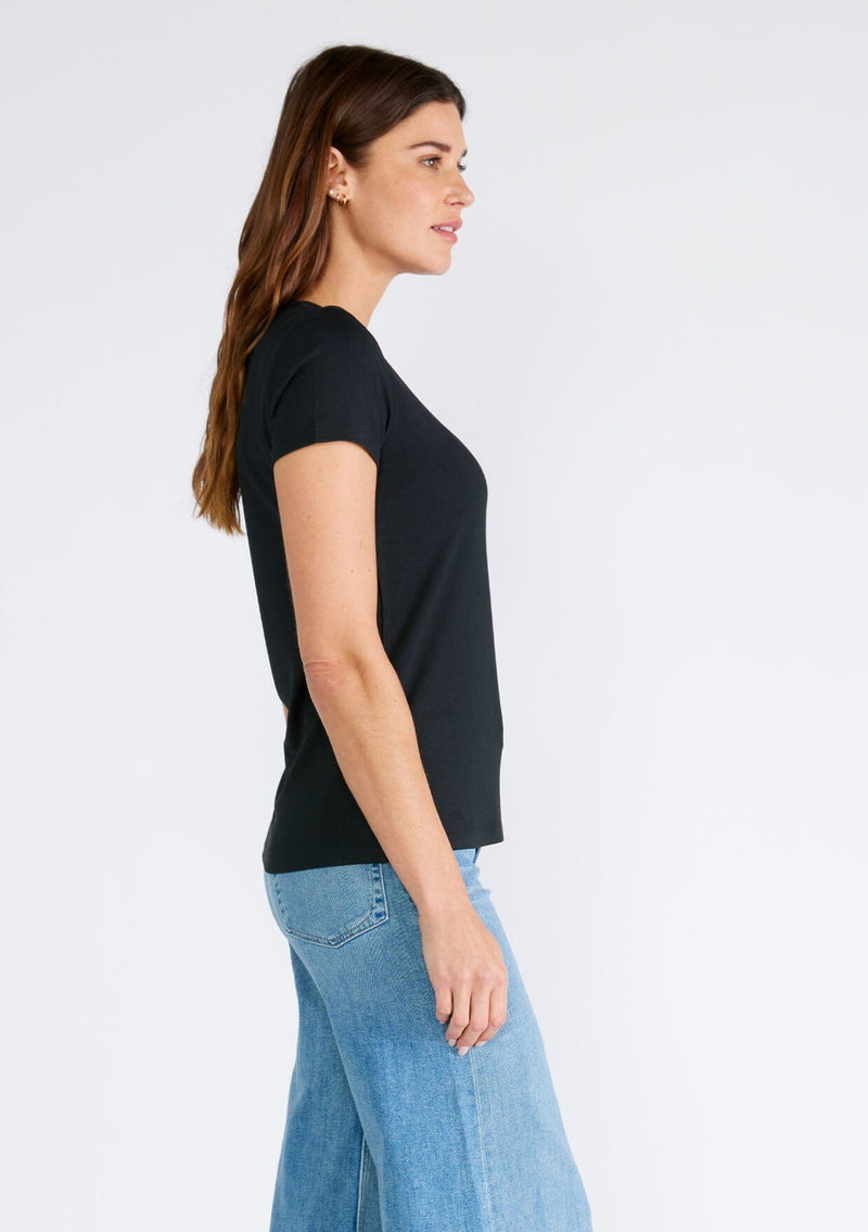 [Color: Black] A side facing image of a brunette model wearing a classic black slim fit tee shirt with a crew neckline and short sleeves, crafted from a ribbed knit. 