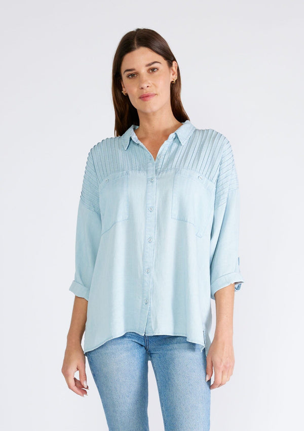 [Color: Bleach Wash] A front facing image of a brunette model wearing a light blue wash Tencel shirt. With long three quarter length sleeves, a button tab sleeve, a collared neckline, a button front, two front patch pockets, and pintuck details. 