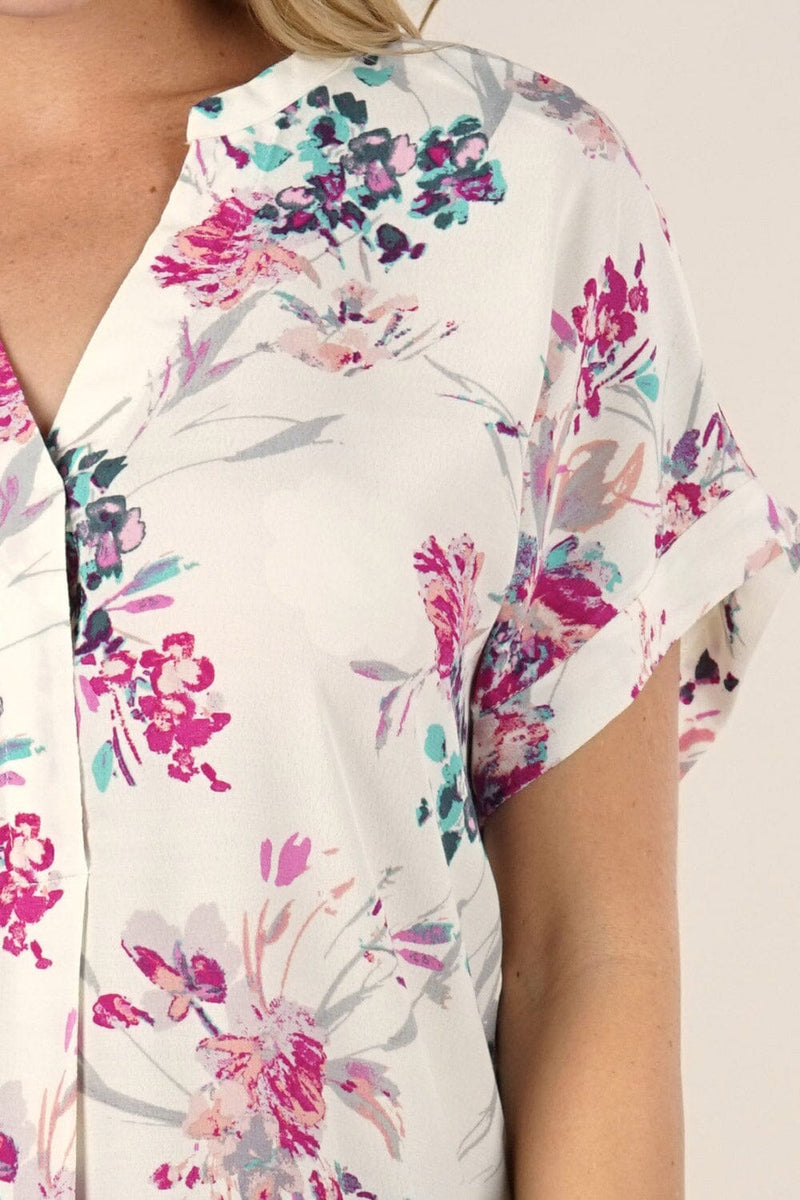 [Color: Ivory/Fuchsia] A detail image of a blonde model wearing a  cute white and pink button front top with pretty floral print and oversized cuffed sleeves.