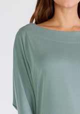 [Color: Slate Green] A close up front facing image of a brunette model wearing a seafoam green soft ribbed knit pullover. With long dolman sleeves and a wide boat neck that can be worn on or off the shoulder. 