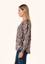 [Color: Dusty Rose/Navy] A side facing image of a blonde model wearing a bohemian fall blouse in a mixed blue and pink floral print. With voluminous long sleeves, smocked elastic wrist cuffs, a split v neckline with ties, and a relaxed fit. 