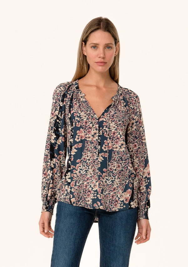 [Color: Dusty Rose/Navy] A front facing image of a blonde model wearing a bohemian fall blouse in a mixed blue and pink floral print. With voluminous long sleeves, smocked elastic wrist cuffs, a split v neckline with ties, and a relaxed fit. 