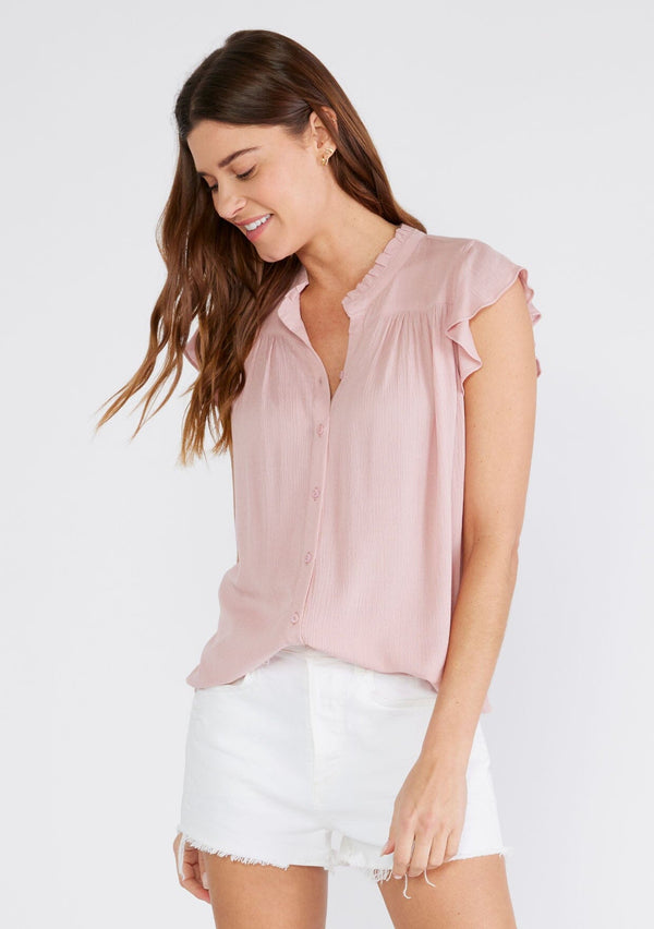 [Color: Dusty Pink] A front facing image of a brunette model wearing a soft pink crinkle gauze short sleeve flutter top with a button front and a ruffled neckline.