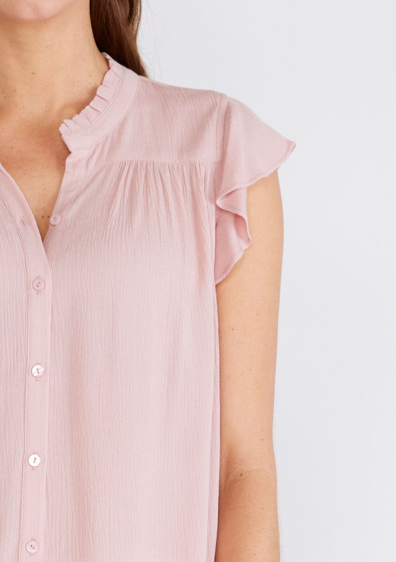 [Color: Dusty Pink] A close up front facing image of a brunette model wearing a soft pink crinkle gauze short sleeve flutter top with a button front and a ruffled neckline.