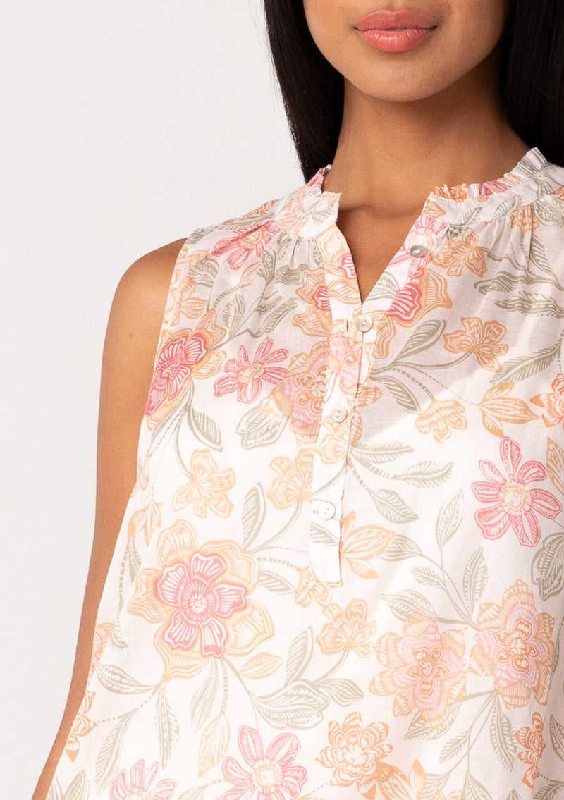 [Color: Natural/Coral] A close up front facing image of a brunette model wearing a lightweight cotton tank top in a pink floral print. With a ruffled neckline, a button front, and a relaxed fit. 