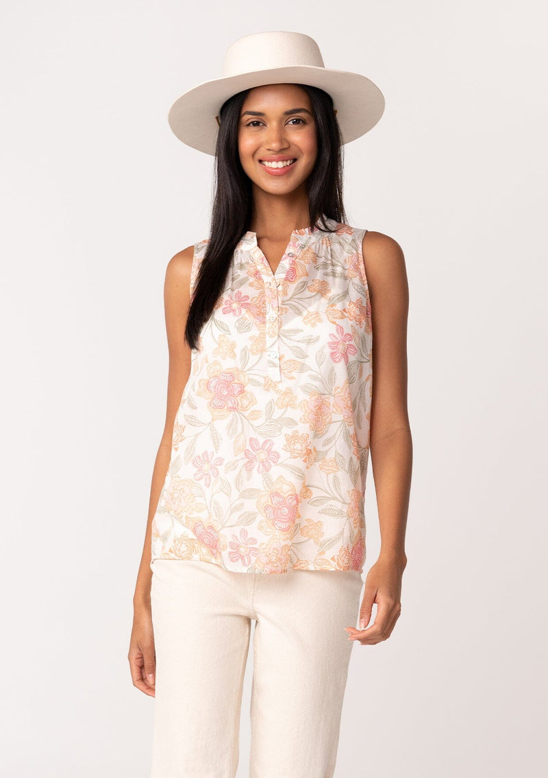 [Color: Natural/Coral] A front facing image of a brunette model wearing a lightweight cotton tank top in a pink floral print. With a ruffled neckline, a button front, and a relaxed fit. 