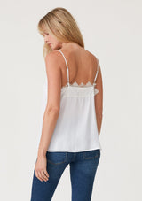 [Color: Chalk] A side facing image of a blonde model wearing a white lace trim camisole with a v neckline, adjustable spaghetti straps, and a flowy relaxed fit.