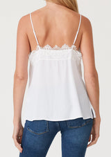 [Color: Chalk] A back facing image of a blonde model wearing a white lace trim camisole with a v neckline, adjustable spaghetti straps, and a flowy relaxed fit.