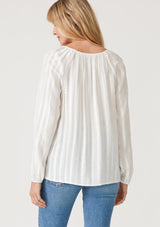 [Color: White] A back facing image of a blonde model wearing a bohemian white blouse with embroidered details. With long raglan sleeves, a round neckline with a single button closure, a front keyhole, and a relaxed fit. 