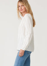 [Color: White] A side facing image of a blonde model wearing a bohemian white blouse with embroidered details. With long raglan sleeves, a round neckline with a single button closure, a front keyhole, and a relaxed fit. 