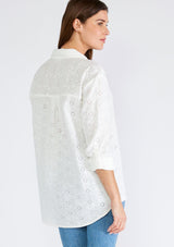 [Color: White] A back facing image of a brunette model wearing a classic white bohemian shirt crafted in embroidered eyelet cotton. With long sleeves, a classic collared neckline, and a button front. 