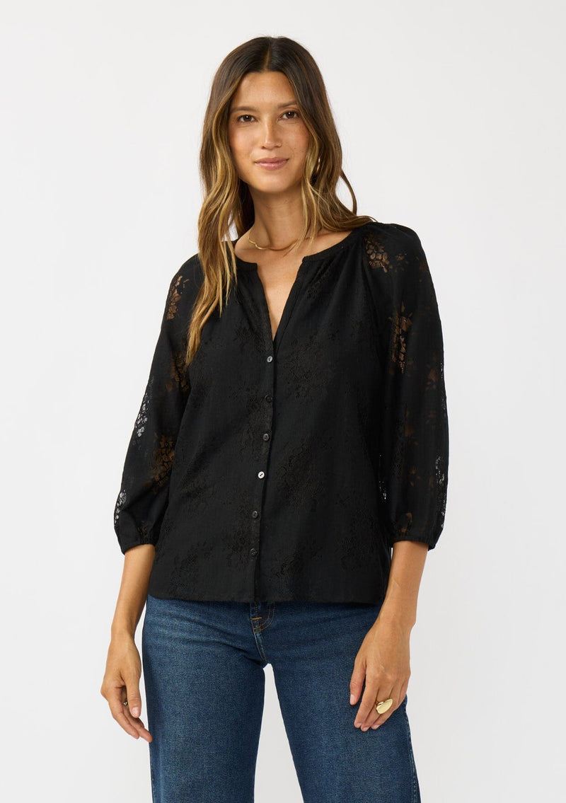 [Color: Black] A front facing image of a brunette model wearing a black lace blouse with a button front, split v-neckline and 3/4 length sleeves. A classic and romantic top for the fall season. 