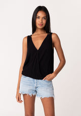 [Color: Black] A front facing image of a brunette model wearing a casual black bohemian summer tank top with a surplice v neckline, an elastic waist, and a back soutache braided detail. 