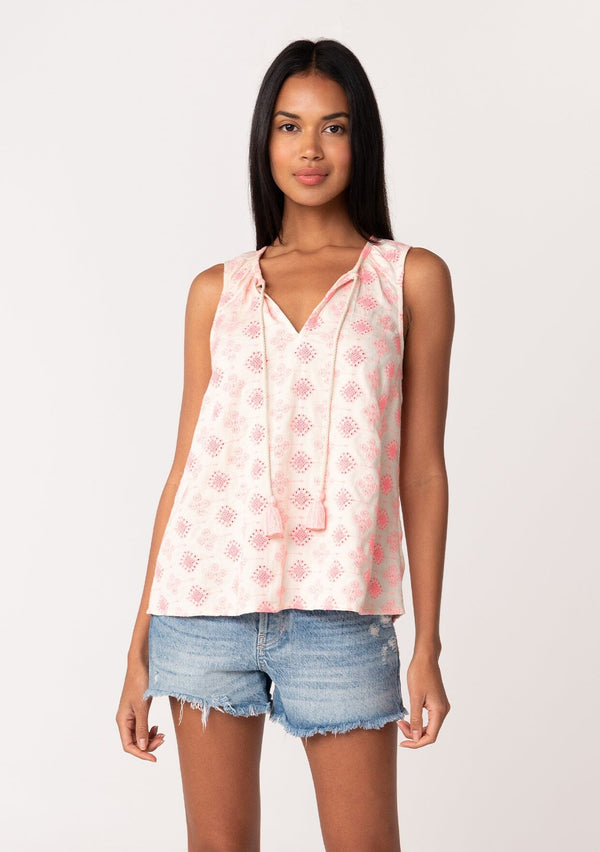 [Color: Natural/Pink] A front facing image of a brunette model wearing a classic sleeveless bohemian blouse in pink embroidery. With a split v neckline and tassel ties. Made with one hundred percent cotton. 