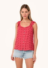 [Color: Fuchsia] A front facing image of a blonde model wearing a pink summer top with embroidered eyelet details. With a button front, flutter straps, and a scoop neckline.