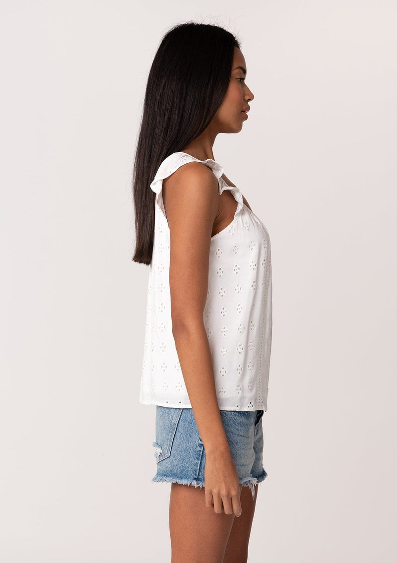 [Color: White] A side facing image of a brunette model wearing a white summer top with embroidered eyelet details. With a button front, flutter straps, and a scoop neckline. 