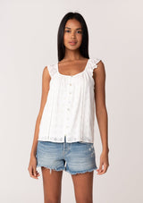 [Color: White] A front facing image of a brunette model wearing a white summer top with embroidered eyelet details. With a button front, flutter straps, and a scoop neckline. 