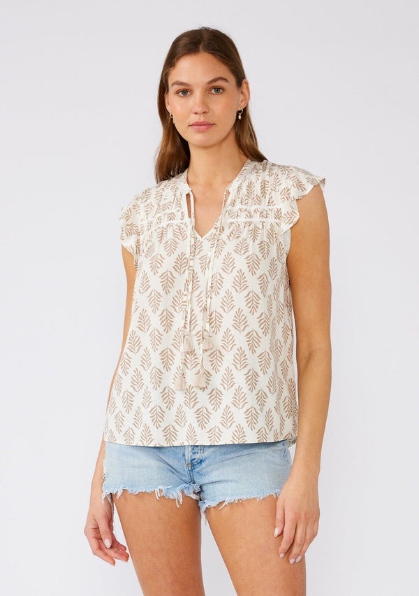 [Color: Latte/Natural] A front facing image of a brunette model wearing a classic bohemian summer top in an ivory and brown bohemian print. With short flutter sleeves, a split v neckline with double tassel ties, and a relaxed fit. 