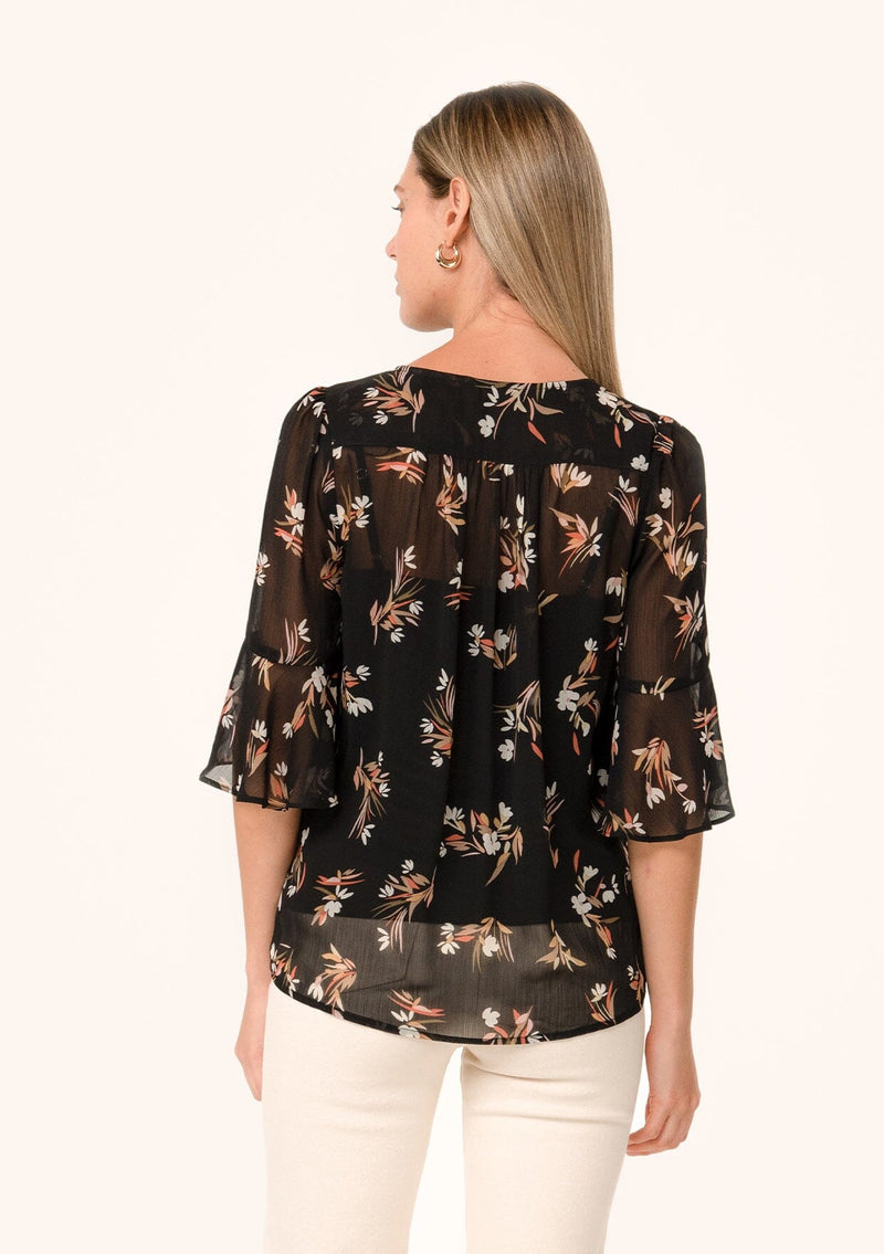 [Color: Black/Peach] A back facing image of a blonde model wearing a delicate chiffon bohemian blouse in a black and peach floral print. With half length flutter sleeves, a v neckline, and a self covered loop button front. 