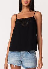 [Color: Black] A close up front facing image of a brunette model wearing a black bohemian camisole with adjustable spaghetti straps, a scoop neckline, a button up back, and lace detail. 