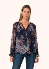 [Color: Navy/Dusty Blue] A front facing image of a blonde model wearing a bohemian fall blouse in a blue floral print. Designed in a metallic clip dot chiffon, with sheer long sleeves, ruffled elastic wrist cuffs, a button loop trimmed v neckline, and a self covered button front. 