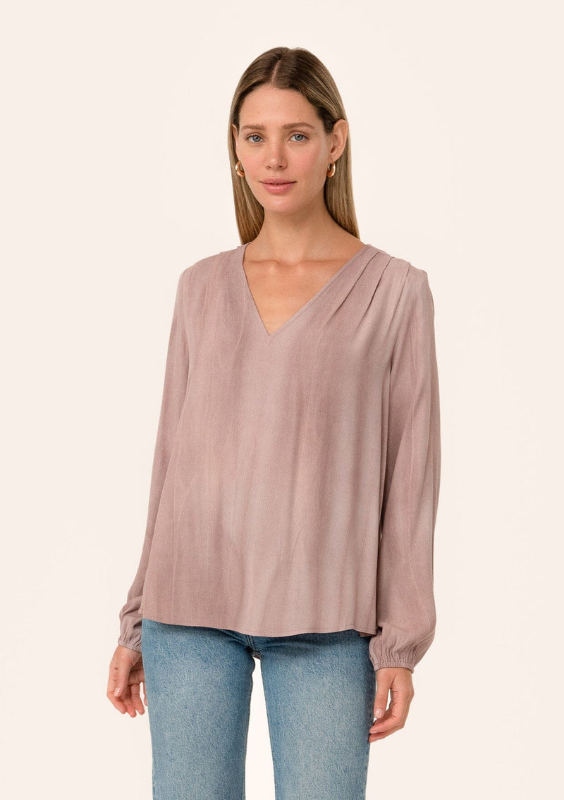 [Color: Rose Water] A front facing image of a blonde model wearing a rose pink bohemian blouse. With long sleeves, a v neckline, and pleated shoulder details. 
