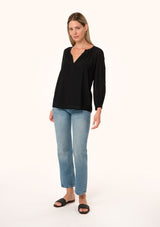 [Color: Black] A full body front facing image of a blonde model wearing a black bohemian fall blouse. With a v neckline, long sleeves, and embroidered detail.