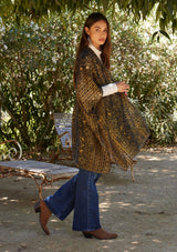 [Color: Gold/Dark Indigo] A side facing image of a brunette model wearing a gold bohemian duster kimono with a dark indigo velvet burnout design. A special occasion kimono with half length sleeves and an open front.