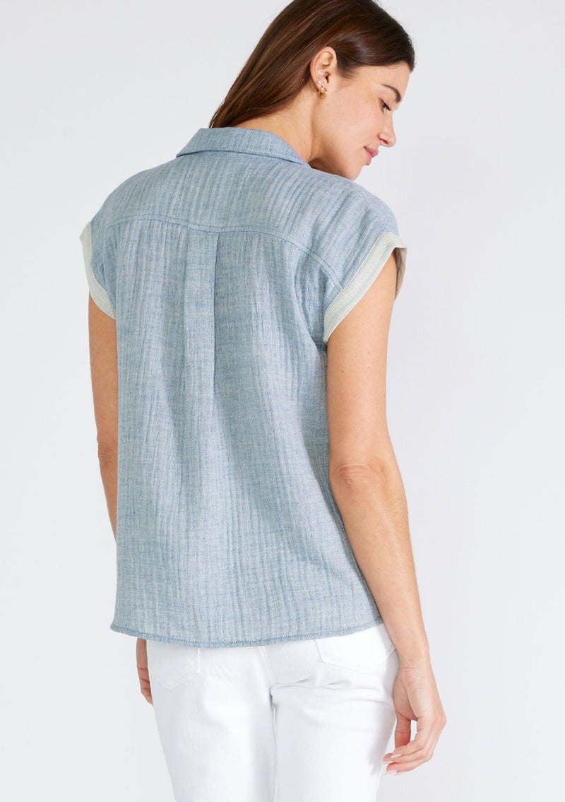 [Color: Dusty Blue] A back facing image of a brunette model wearing a light blue short sleeve shirt crafted from soft cotton gauze. With a button up front, a collared neckline, a front patch pocket, and short contrast cap sleeves. 