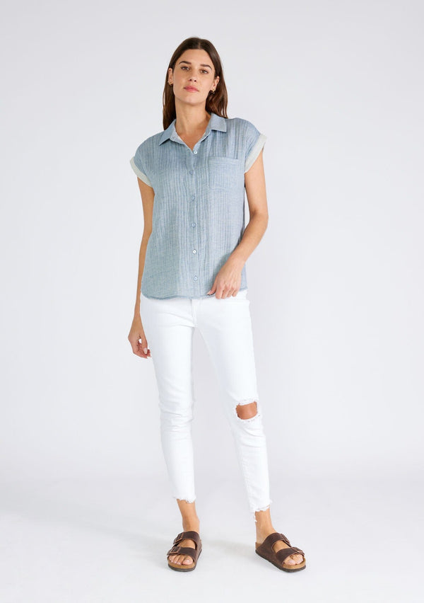 [Color: Dusty Blue] A full body front facing image of a brunette model wearing a light blue short sleeve shirt crafted from soft cotton gauze. With a button up front, a collared neckline, a front patch pocket, and short contrast cap sleeves. 
