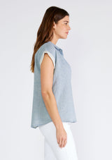 [Color: Dusty Blue] A side facing image of a brunette model wearing a light blue short sleeve shirt crafted from soft cotton gauze. With a button up front, a collared neckline, a front patch pocket, and short contrast cap sleeves. 
