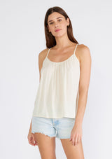 [Color: Ivory] A front facing image of a brunette model wearing an ivory bohemian tank top with a scooped neckline, spaghetti straps, and a sheer lace racerback detail. 