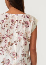 [Color: Natural/Dusty Wine] A close up back facing image of a brunette model wearing a bohemian resort top in a vintage inspired off white and pink floral print. With a scoop neckline, short cap sleeves, lace trim, pintuck details, and a self covered button up back. 