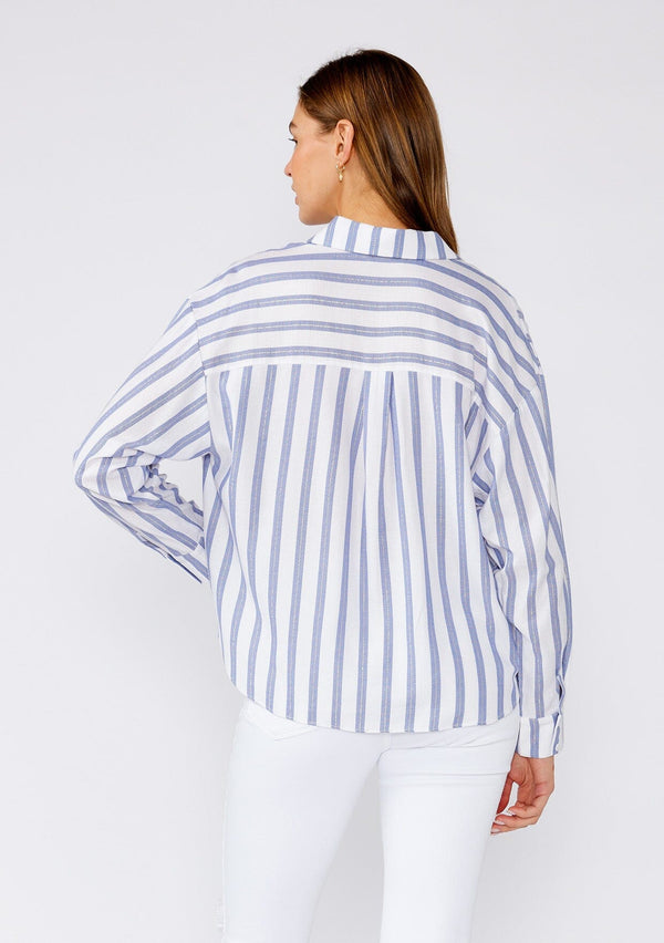 [Color: White/Blue] A back facing image of a brunette model wearing a relaxed spring shirt in a white and blue stripe and a metallic gold thread detail. With long sleeves, a dropped shoulder, a v neckline, a collared neckline, a button front, and a knot waist detail. 