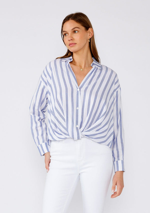 [Color: White/Blue] A front facing image of a brunette model wearing a relaxed spring shirt in a white and blue stripe and a metallic gold thread detail. With long sleeves, a dropped shoulder, a v neckline, a collared neckline, a button front, and a knot waist detail. 