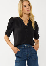 [Color: Black] A front facing image of a blonde model wearing a casual black puff sleeve top with a ruffled neckline, button front, and a gathered sleeve detail. Effortless and versatile for easy layering or wearing on its own. 