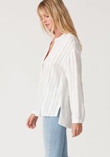 [Color: White] A side facing image of a blonde model wearing a bohemian white shirt with embroidered detail. With long sleeves, a v neckline, a button up front, and a relaxed fit. 