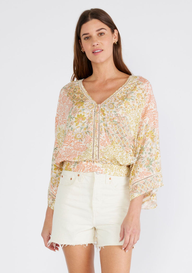 [Color: Dusty Peach/Rust] A half body front facing image of a brunette model wearing a classic button front bohemian top with dramatic billowy half length sleeves, designed in a peach and rust mixed floral print. With a v neckline, sheer lattice trim, and a slightly cropped length.