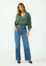 [Color: Forest Green] A front facing image of a brunette model wearing a green bohemian top with tonal embroidery, wide sleeves, lattice trims, a button front, and a v neckline. 