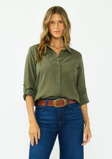 [Color: Olive] A front facing image of a blonde model wearing a green button front shirt crafted in a sheer textured cotton. Featuring a collared neckline, high low hemline, and long roll tab sleeves. Paired with a dark wash denim. 
