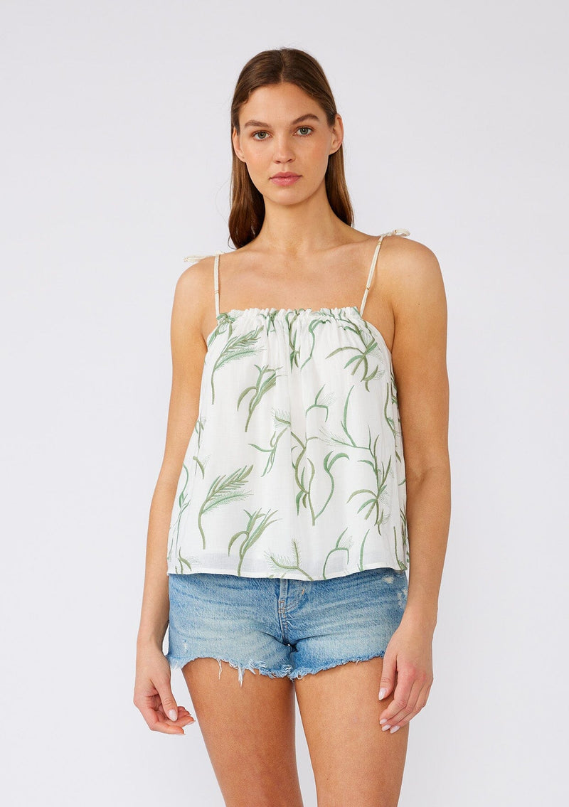 [Color: Off White/Green] A half body front facing image of a brunette model wearing a white cotton bohemian tank top with contrast green embroidery. With rope straps, adjustable shoulder ties, a ruffled neckline, and a flowy fit. 