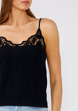 [Color: Black] A close up front facing image of a brunette model wearing a classic black bohemian camisole with lace detail along the neckline. With adjustable spaghetti straps and a scooped neckline. 