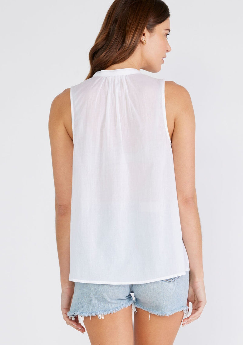 [Color: Chalk] A back facing image of a brunette model wearing a bohemian cotton tank top in a white. With a v neckline, a loose, tent silhouette, and pleated details along the front.