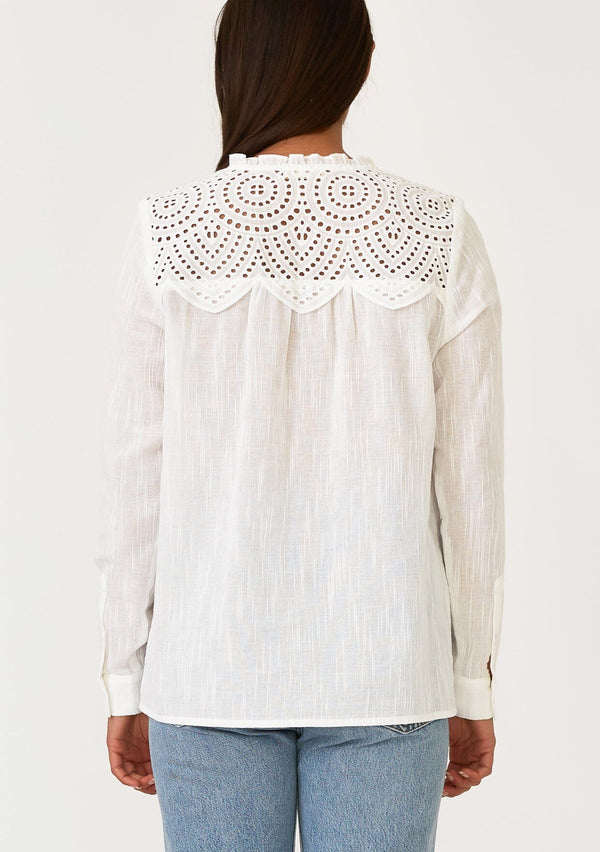 [Color: White] A back facing image of a brunette model wearing a white bohemian button front blouse with a ruffled round neckline, a self covered button front, long sleeves, and an eyelet yoke detail. 