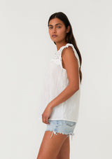 [Color: White] A side facing image of a brunette model wearing a white bohemian spring top with short cap sleeves, a split v neckline, and an eyelet lace yoke. 